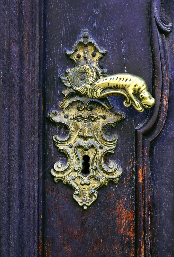 捷克布拉格配有装饰手和钥匙孔的旧木门图片