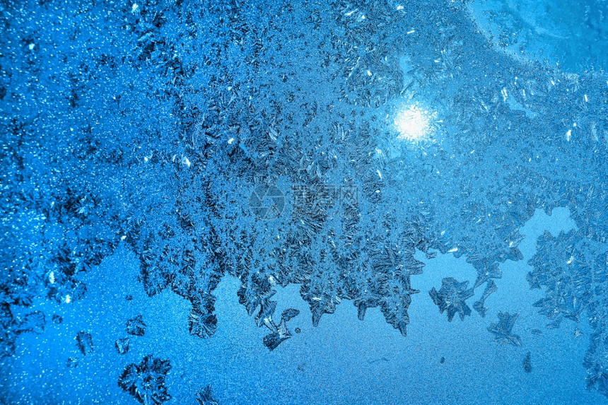 美丽的冰面图案和玻璃上的阳光蓝色冬季纹理图片