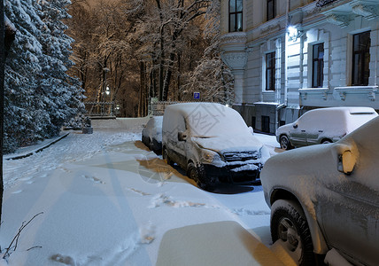 乌克兰利沃夫市中心美丽的黄昏冬季城市景观汽车被雪覆盖了图片