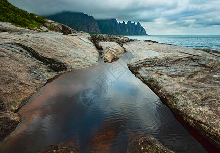 斯帕丰莱奥克挪威Senja市Ersfjord的沙滩上有潮汐浴夏季极地日夜海岸远处的龙牙岩背景