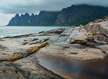 斯帕丰莱奥克挪威Senja市Ersfjord的沙滩上有潮汐浴夏季极地日夜海岸远处的龙牙岩背景