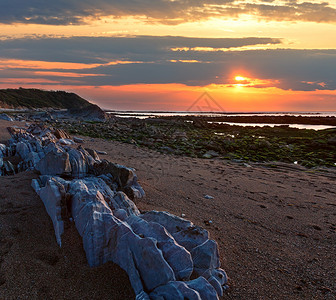 帕德卢斯从海滩向日落的岸看大石块靠近法国圣让德卢斯比凯湾背景