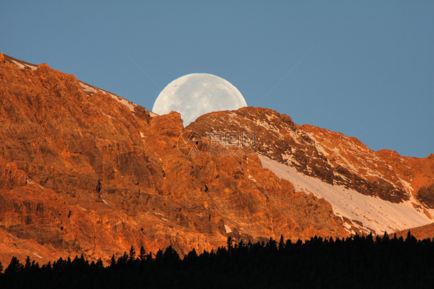 满月在艾伯塔风景的山后图片