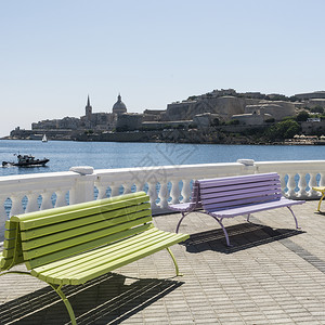 在瓦莱塔河堤岸的多姿彩公园长椅上在马耳他海湾背景上宣传图片
