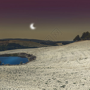 西班牙在月亮光照收割后在破碎的田地之间灌溉池塘图片