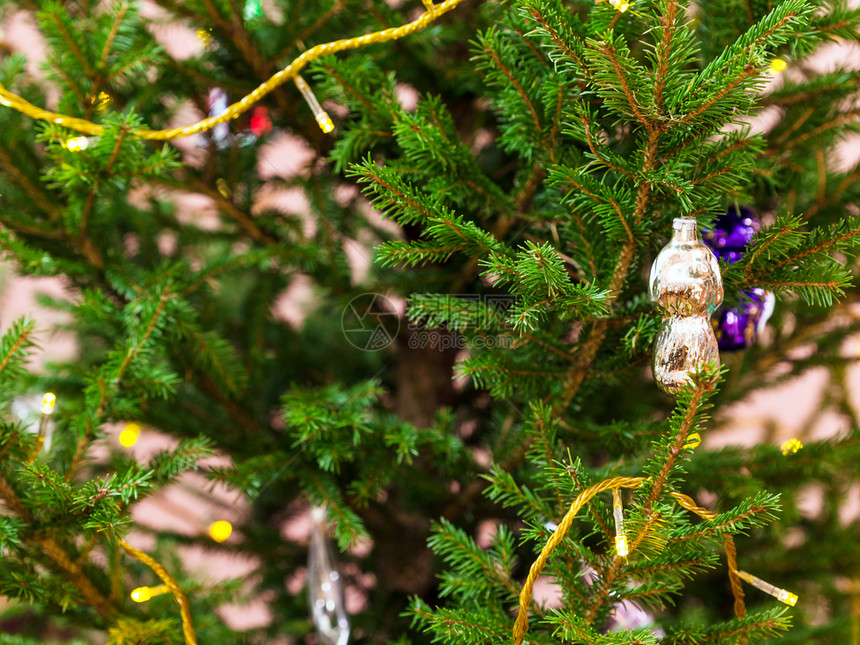 Xmas背景室内天然圣诞树上的玻璃玩具和园林灯光图片