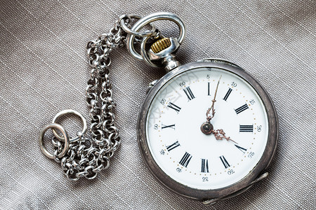 灰色纺织品背景带链条的老式银袖手表图片