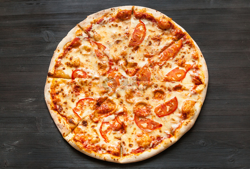 上面有意大利披萨黑棕色木板上含乳酪和西红柿的意大利披萨图片