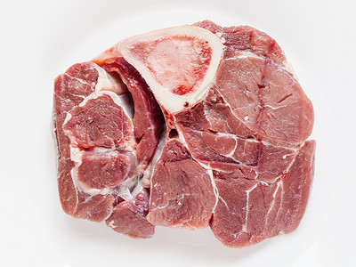 白盘上意大利菜Osssobuco上方带有骨髓的原小牛肉片面视图图片