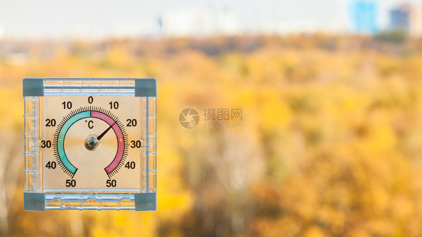 家用窗户的外温度计和阳光暖的秋天背面模糊黄色城市花园图片