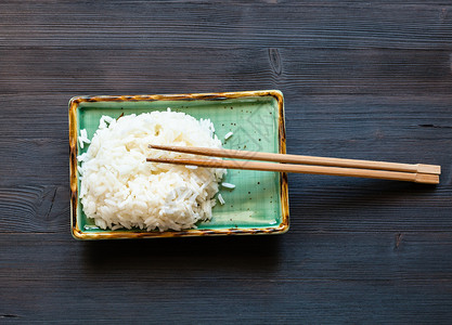 黑棕色桌子上绿板的筷子煮熟大米的风景图片