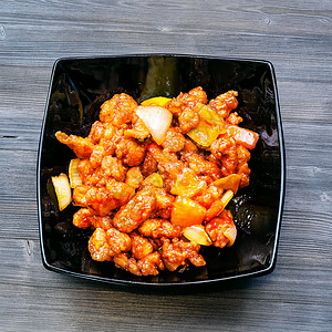 菜黑碗炸鸡菠萝红辣椒和黑木板洋葱甜和酸鸡图片