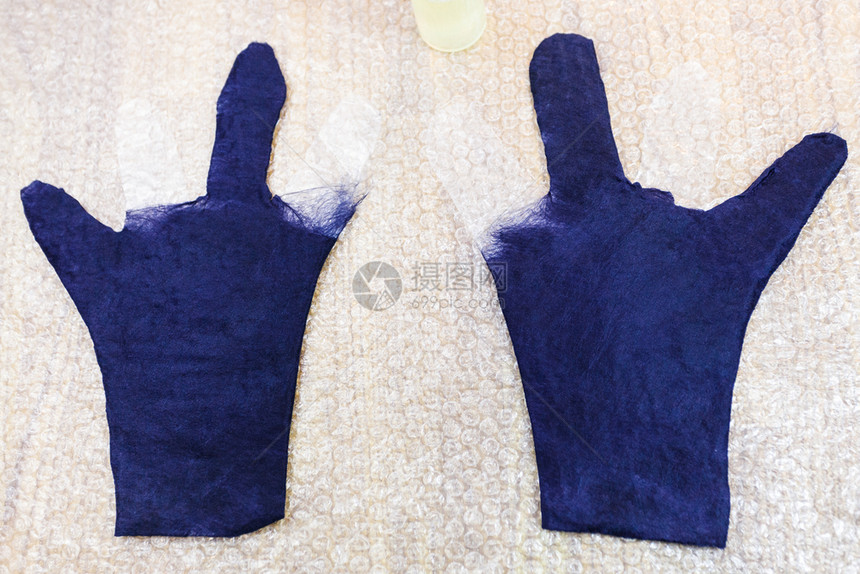 使用湿感觉工艺蓝色梅里诺羊毛手套部分由垫子上浸湿的切割式手套制成图片