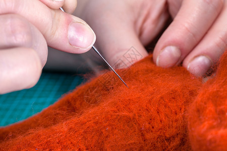 使用针感应工艺来修补羊毛手套的硕士班手工艺人用针感应合身的衣物图片