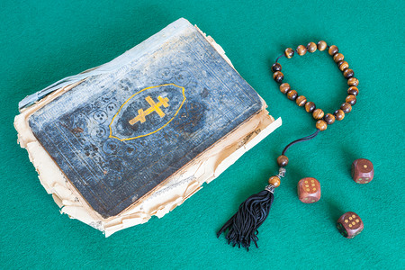 古旧的圣诗书担心珠子和三只木骰放在绿色烤肉桌上图片
