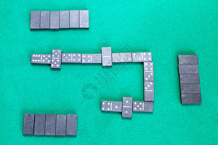 Dominoes棋盘游戏的场绿色烤桌上有黑瓷砖的游戏顶部视图图片