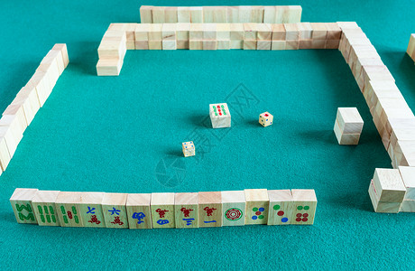 麻将块玩家设置在麻将游戏开始时的中以瓷砖为基的战略棋盘游戏在绿色面包桌上背景