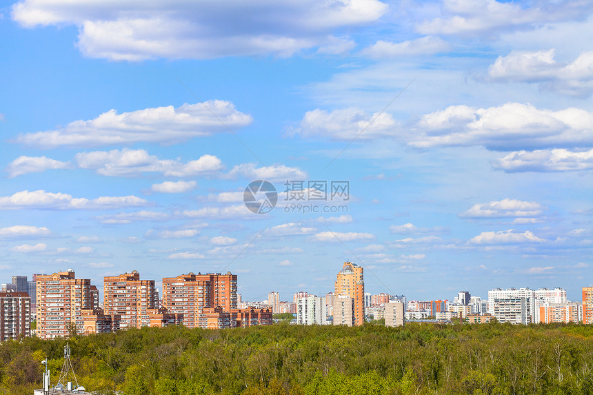 在阳光明媚的春天城市公园和住宅区上空有白云的蓝色天空图片