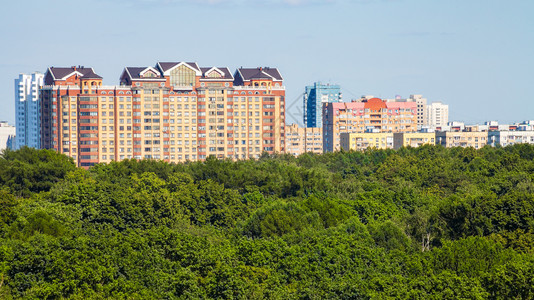 阳光明媚的夏日照耀绿色城市公园和寓房屋的全景图片