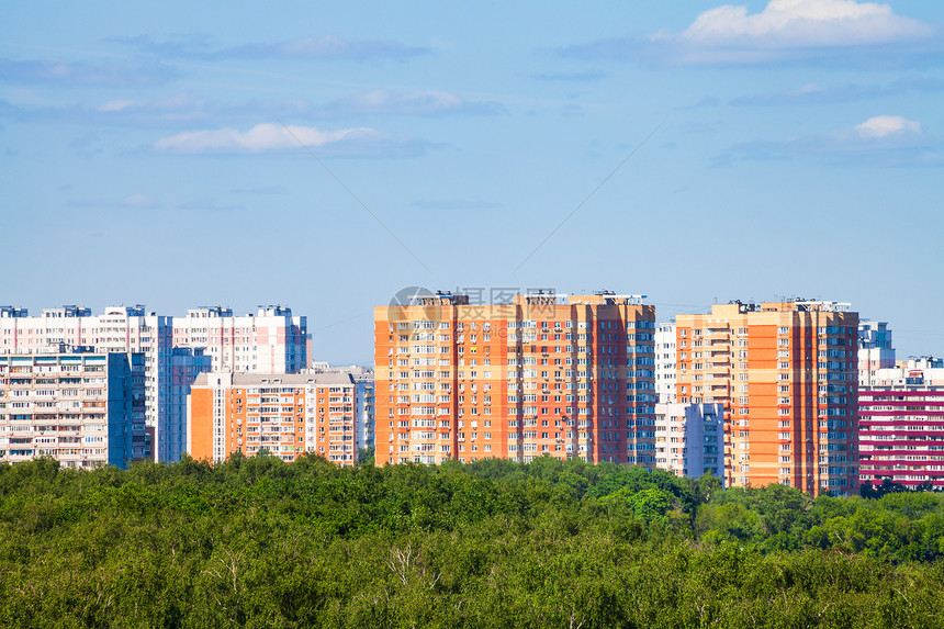 在阳光明媚的夏日蓝天下有民宅和绿色城市公园图片