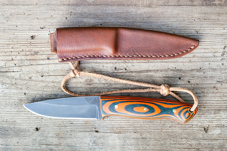 西洋剑剑鞘手工制成黑色钢刀用自制环氧和橙色织物手柄在旧木板上工缝制皮层背景