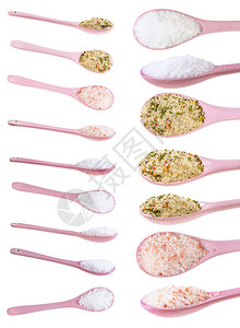 由粉色陶瓷勺制成各种盐类在白色背景上隔离图片