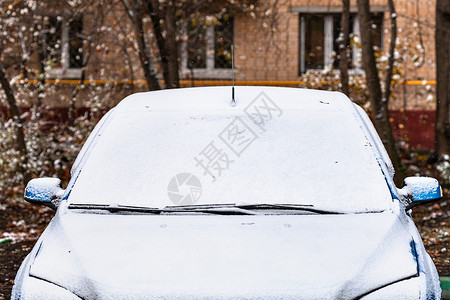在寒冬秋天下雪在公寓房子前面的汽车上第一次下雪图片