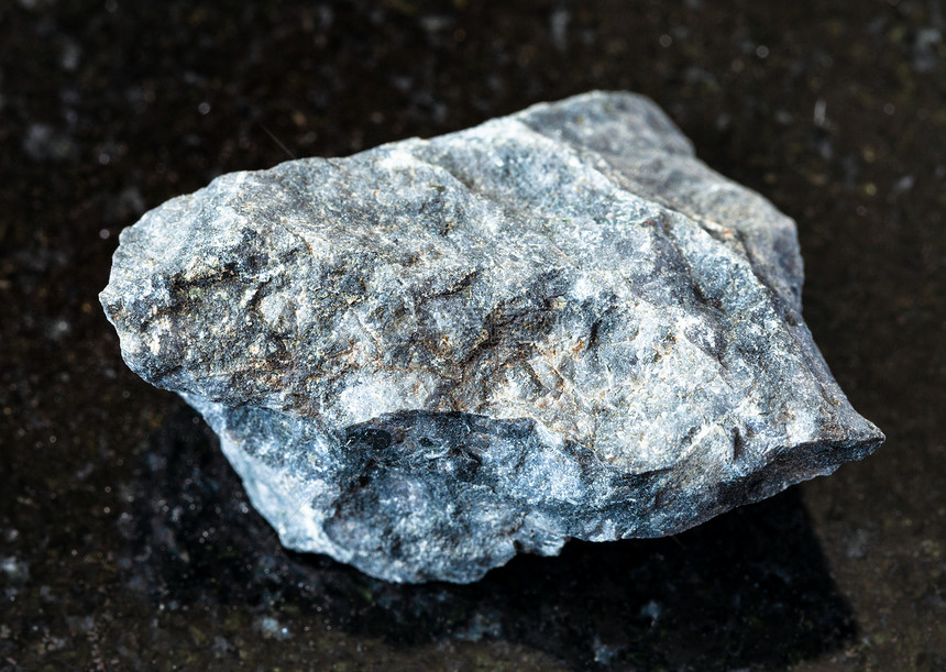 地质采集的天然矿物样本封存黑花岗岩背景的未粉碎灰色巴萨岩图片