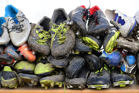 用过的一堆泥脏橄榄球鞋运动背景肮脏的体育场背景图片