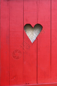 洞心形紧贴在红色木制门窗上的心脏形状红色的背景图片