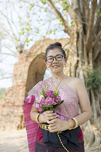 泰国女人露齿笑脸站着手里拿粉红色的莲花束微笑露齿的常设图片