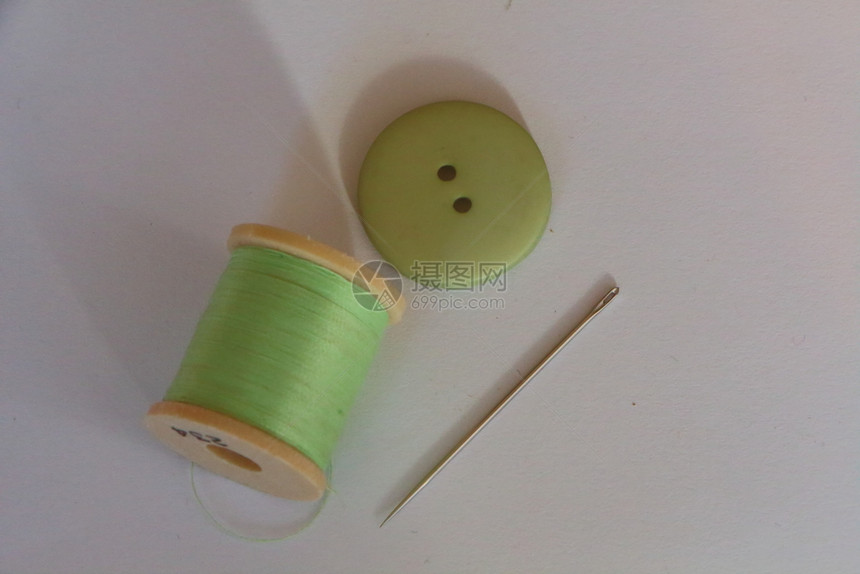 阀芯为了衣服用于缝纫针和绿色按钮的线卷轴图片