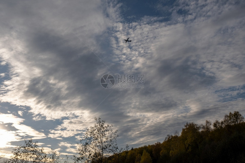 轮廓航空多云的在秋天森林上与美丽的云天空对抗大飞机休眠图片