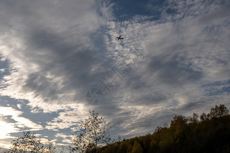 轮廓航空多云的在秋天森林上与美丽的云天空对抗大飞机休眠图片