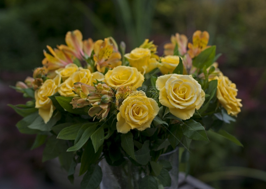一种预设花束瓶中的黄玫瑰和绿叶图片
