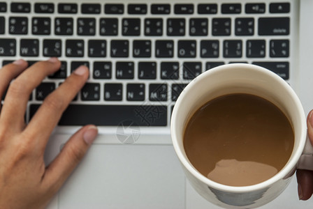 笔记本电脑放松保持键盘和右手左缝合握着咖啡杯的拳头和右手图片