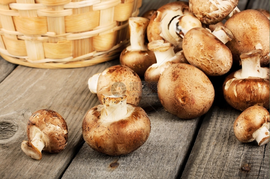 蔬菜木制背景上带篮子的生鲜蘑菇新食物图片