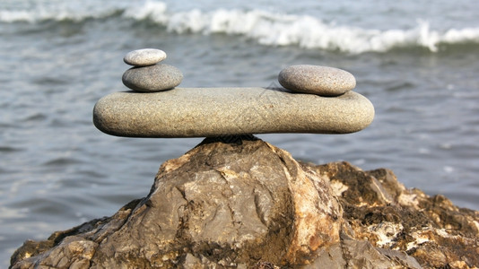 符号天平由各种形状的石头制成海滩平衡户外图片