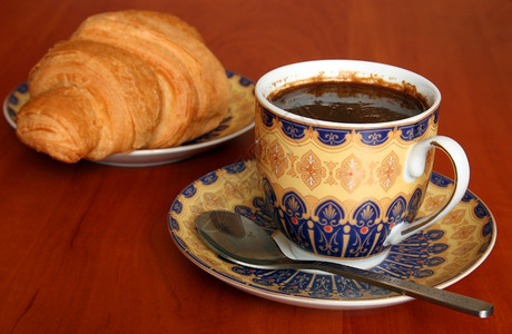 一杯咖啡含羊角面包浅水深的露地咖啡聚焦于杯子上场地盘重点背景图片