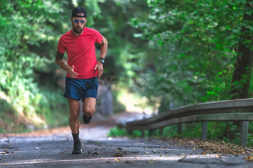 上坡男人肌肉发达一名运动员在山坡沥青路上跑步图片