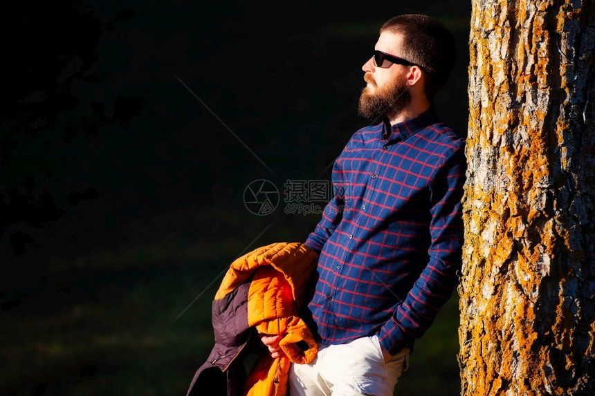 靠在树桩边休息的男性图片