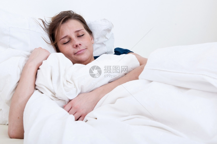 一个睡在床上的女孩拿着毯子躺在床上睡眠患病的黑发图片