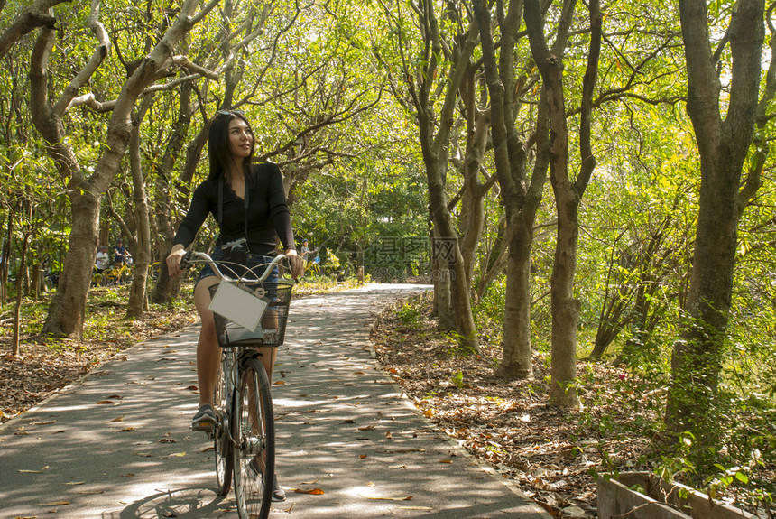 成人年轻妇女在花园里享受骑自行车的乐趣活动骑术图片