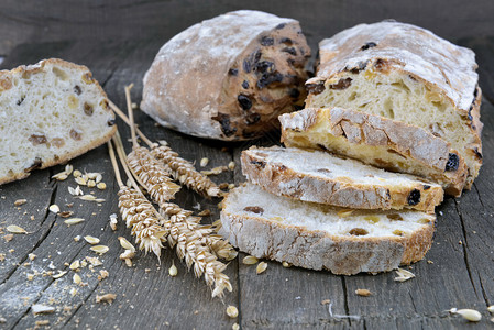 木制的乡村切片面包葡萄和生锈木板上的玉米耳朵图片