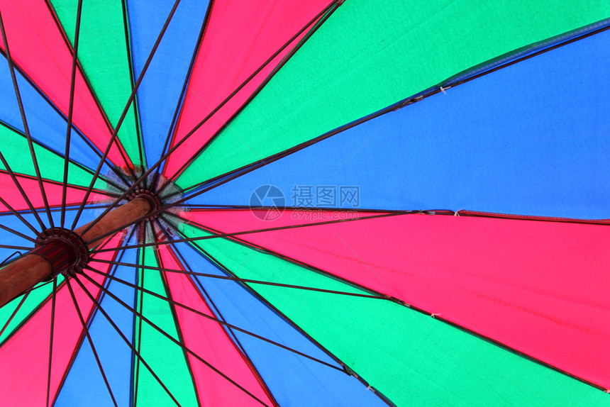太阳在下面在色彩多的海滩伞下作为背景图片