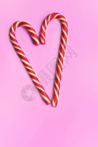 粉色的问候手杖在粉红背景下形成心脏的糖果甘蔗图片