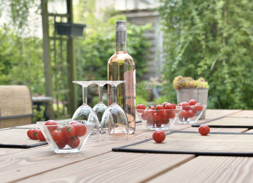 木制的杯子酒瓶和西红柿放在花园露台的饮用水桌上植物葡萄酒图片