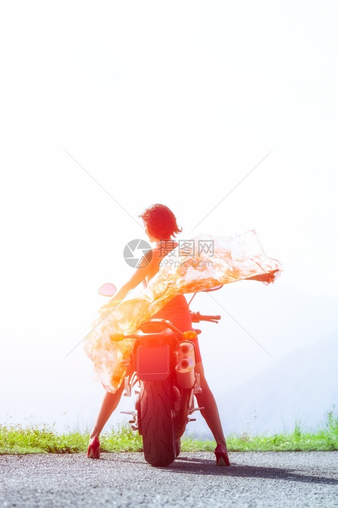 向观看摩托车上的女人站着戴围巾朝太阳走来逃脱图片