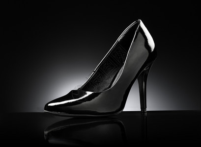 在黑色反射背景上抽动黑光亮的女士们脚跟鞋光滑反的高图片