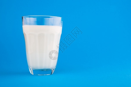 超过营养喝玻璃中的牛奶蓝底背景图片